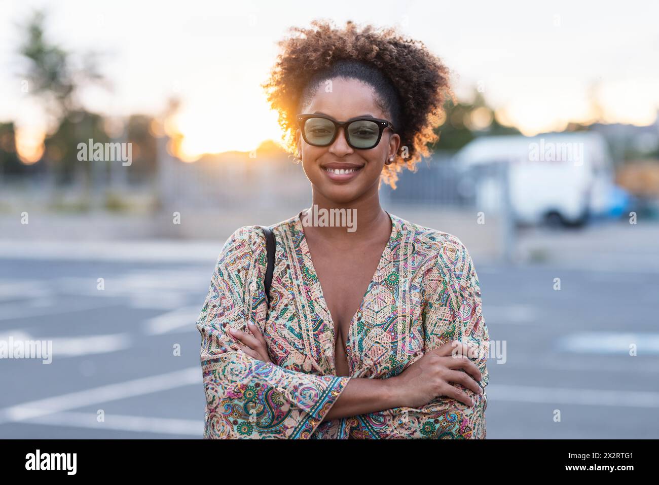 Lächelnde Frau mit überkreuzten Armen auf dem Parkplatz Stockfoto
