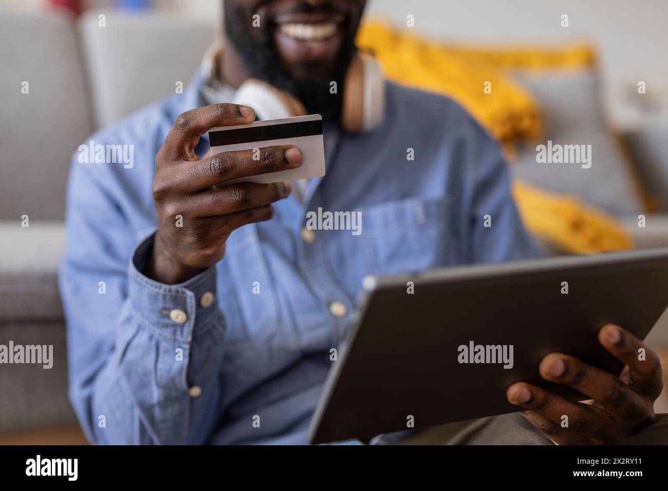 Lächelnde, nicht binäre Person, die mit Kreditkarte auf einem Tablet-PC bezahlt Stockfoto