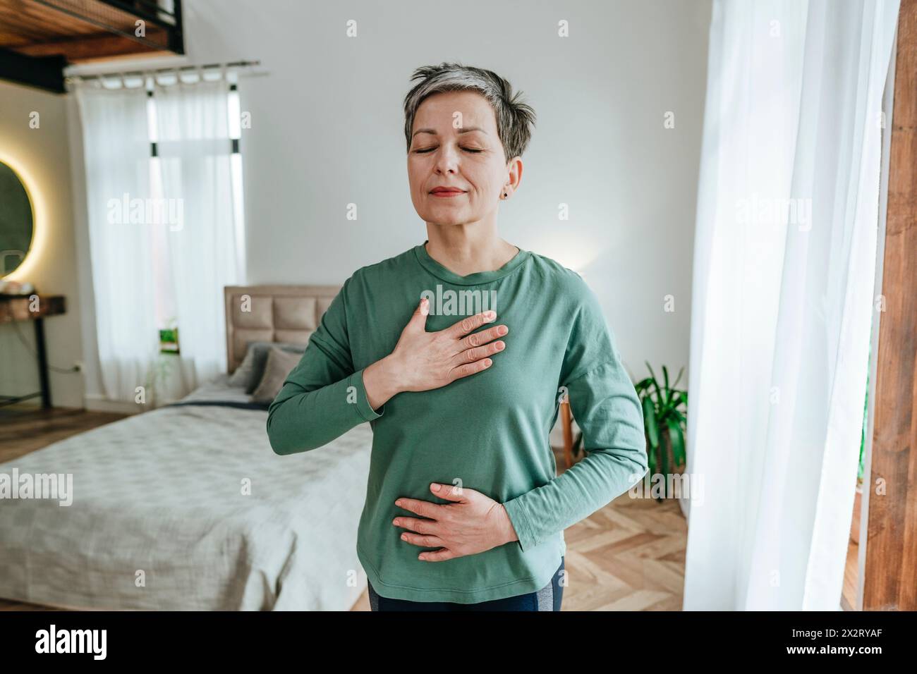Frau übt Atemübungen mit geschlossenen Augen zu Hause Stockfoto