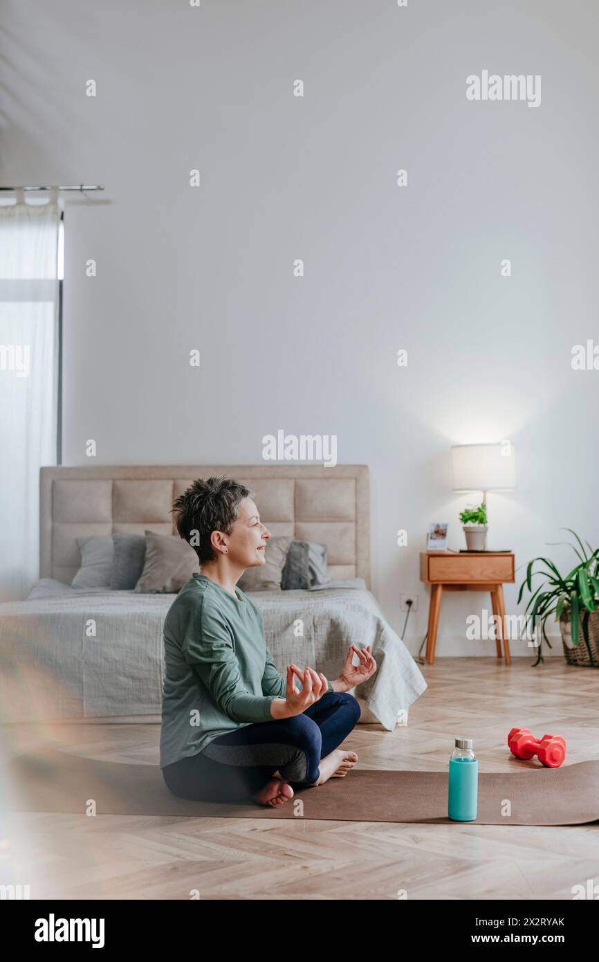 Frau, die zu Hause Yoga auf einer Trainingsmatte macht Stockfoto