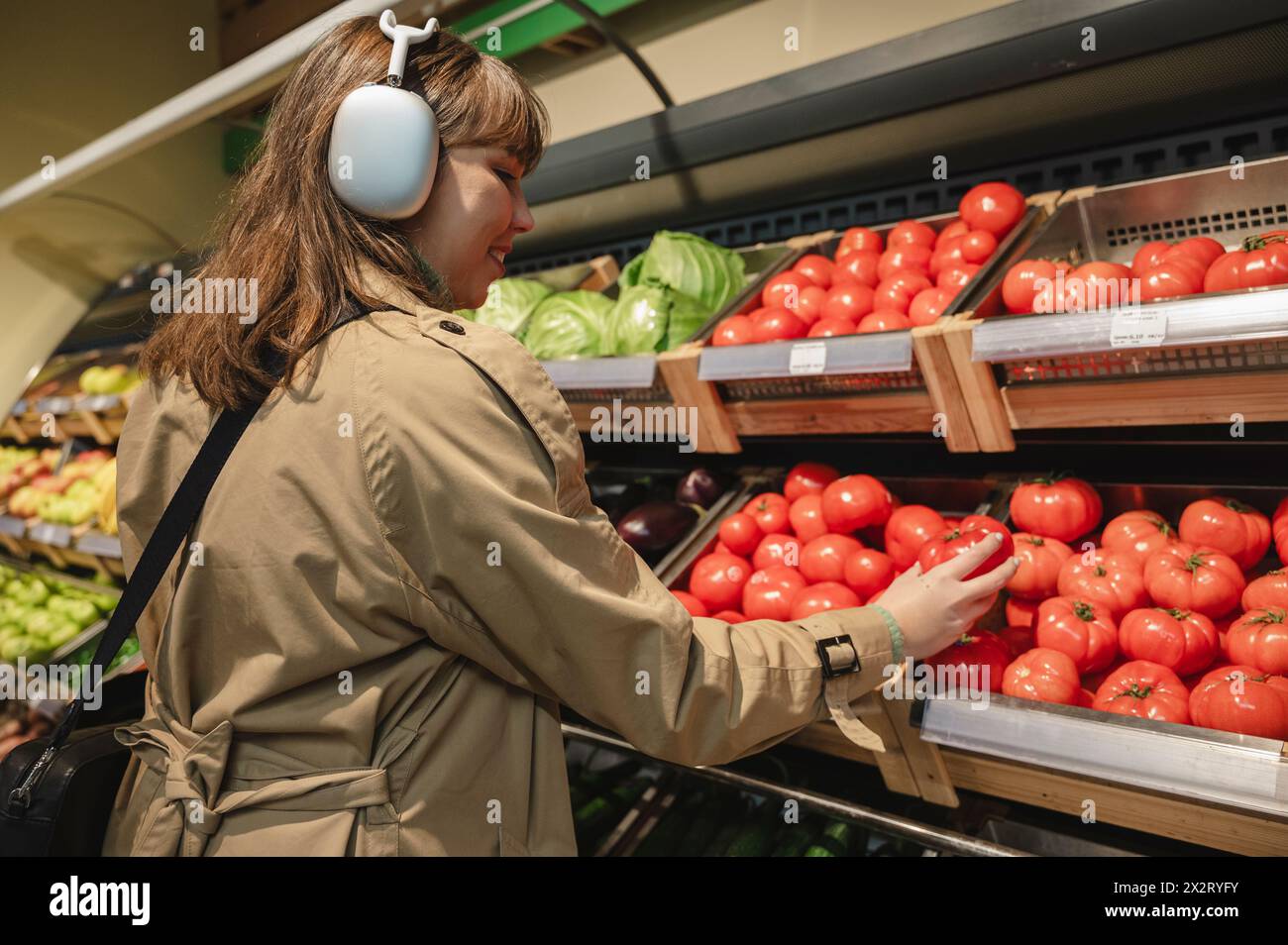 Junge Frau, die Tomaten im Supermarkt aussucht Stockfoto