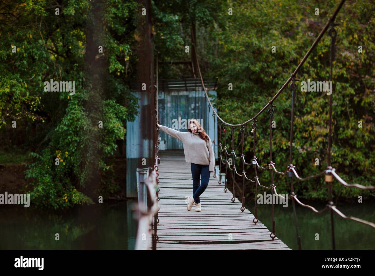 Reife Frau, die im Park auf einer Fußgängerbrücke steht Stockfoto