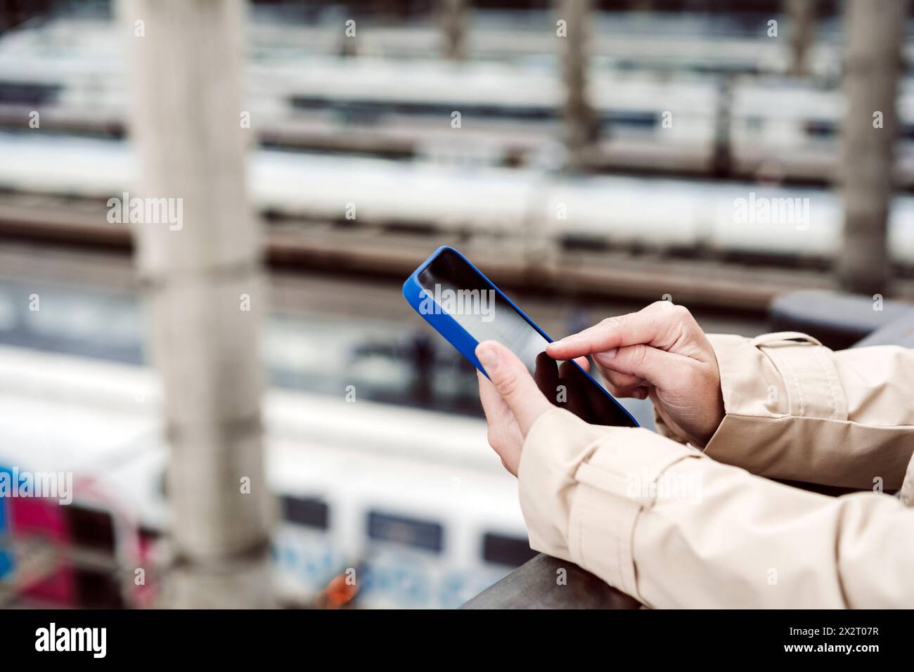 Frau, die am Bahnhof ein Smartphone scannt Stockfoto