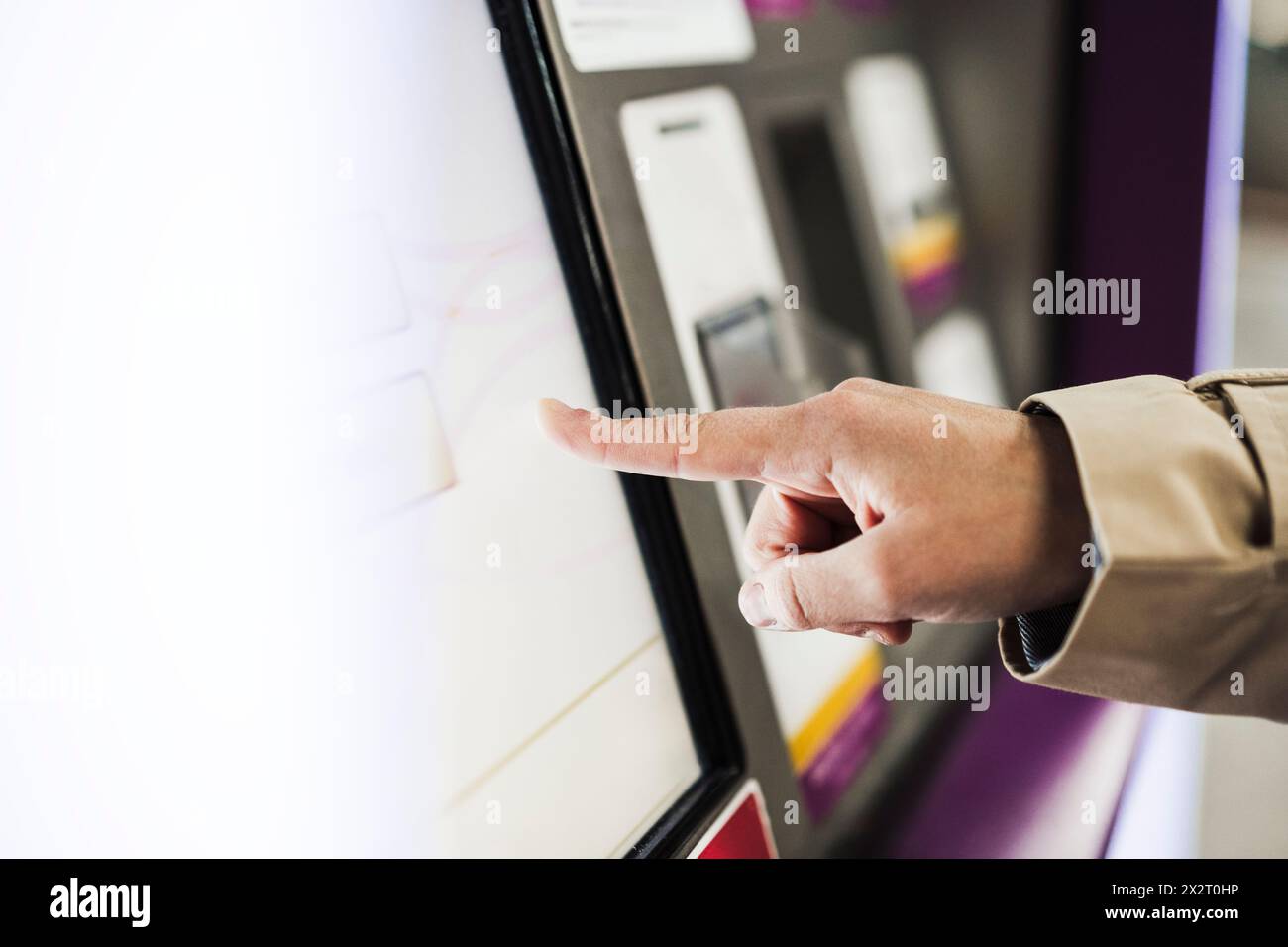 Frau, die den Bildschirm des Fahrkartenautomaten am Bahnhof berührt Stockfoto