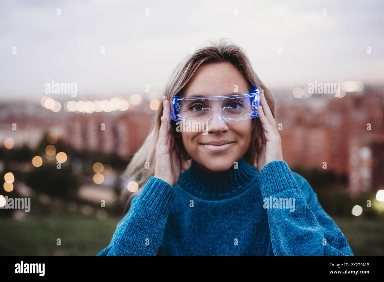 Lächelnde Frau, die in der Abenddämmerung eine kluge Brille trägt Stockfoto