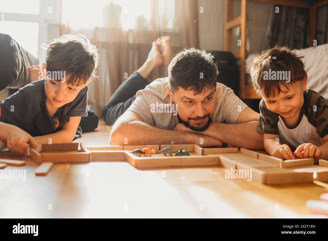 Vater und Söhne spielen zu Hause Freizeitspiele auf dem Boden Stockfoto