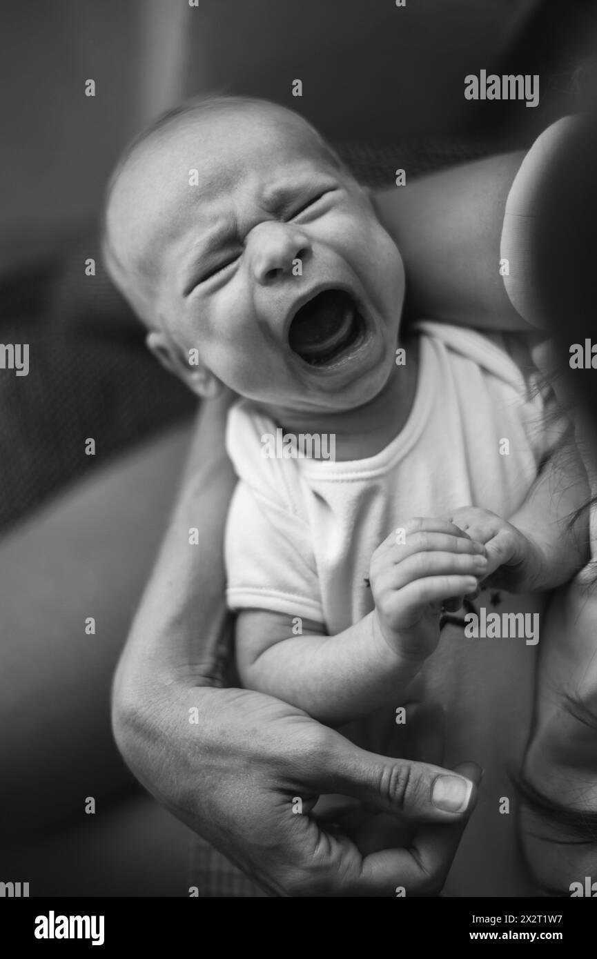 Weinender Junge in den Armen der Mutter zu Hause Stockfoto