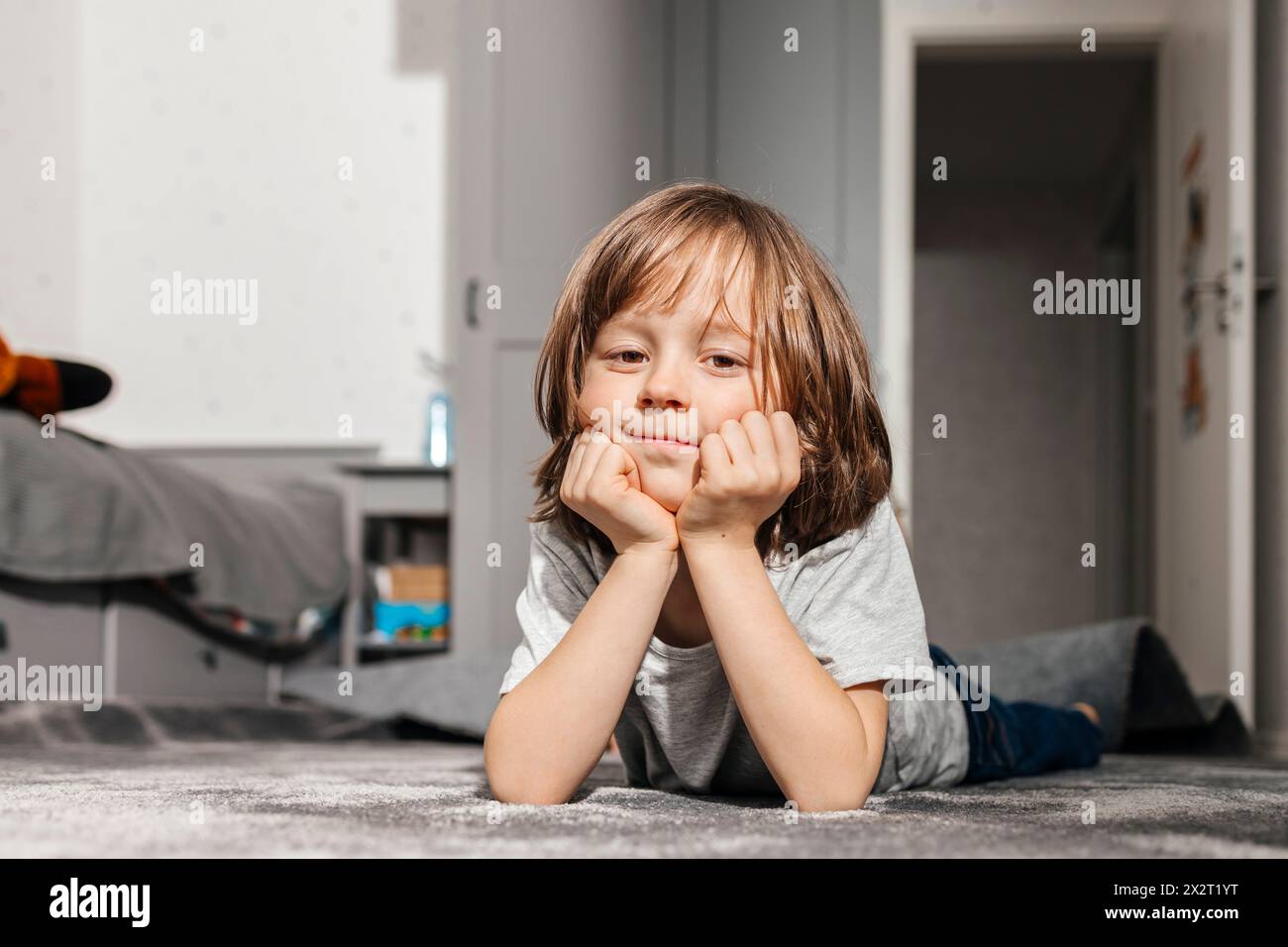 Junge, der zu Hause auf dem Teppich liegt Stockfoto