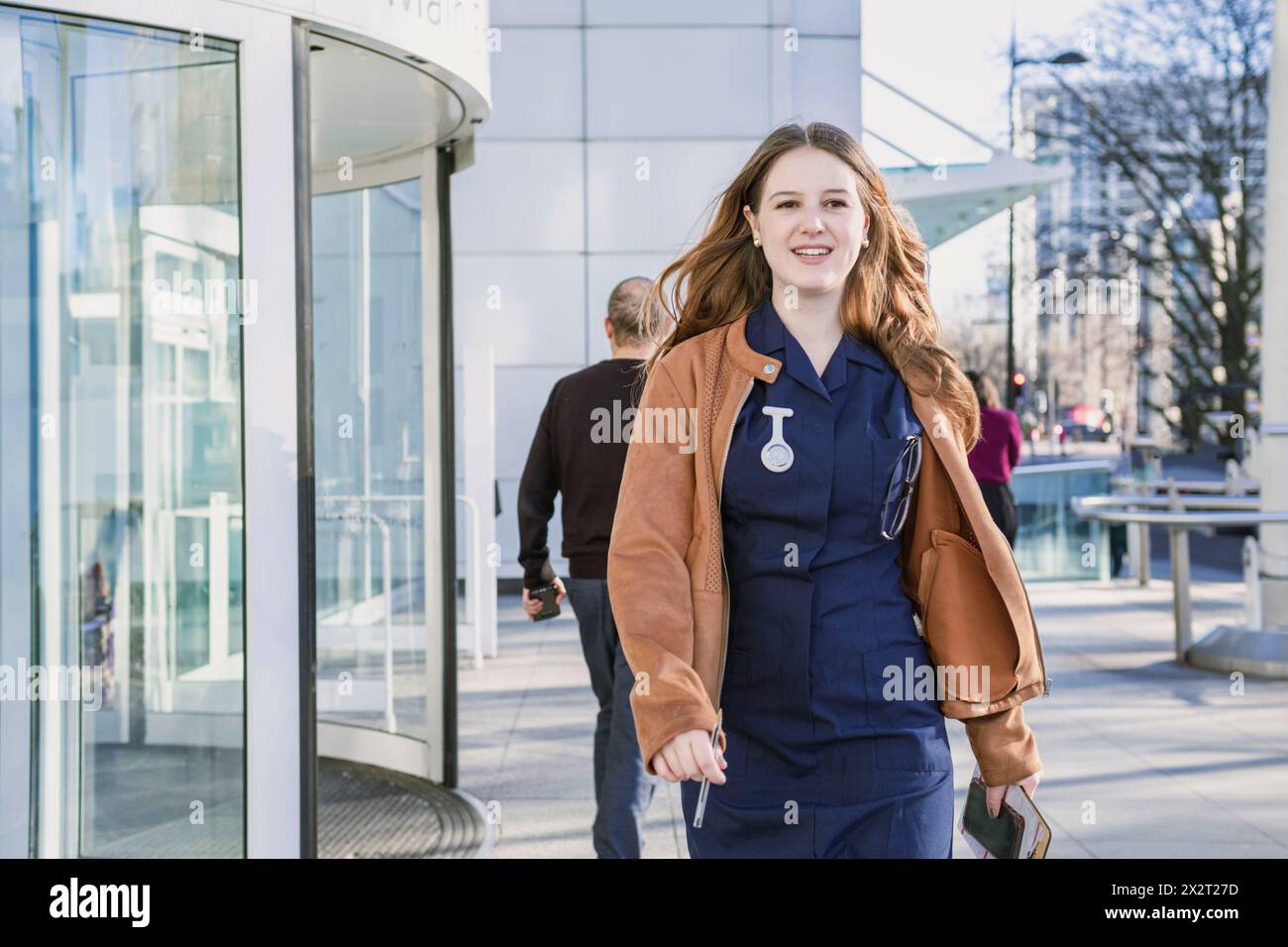 Lächelnder Arzt, der in der Nähe des Gebäudeeingangs spaziert Stockfoto