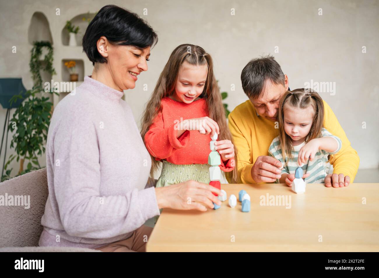 Glückliche Großeltern spielen Spiel mit Enkelkindern zu Hause Stockfoto