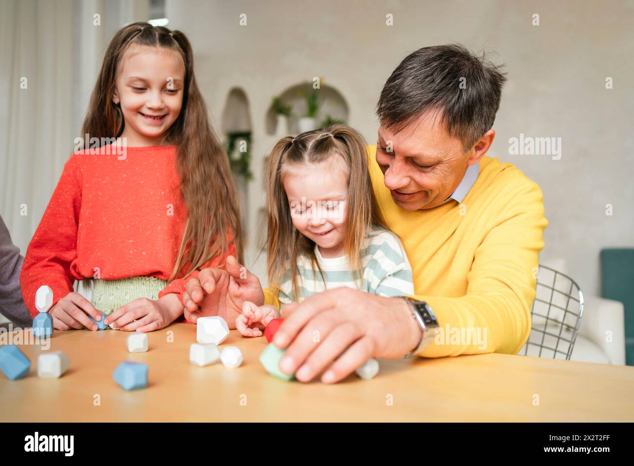 Großvater spielt zu Hause mit Enkelinnen Stockfoto