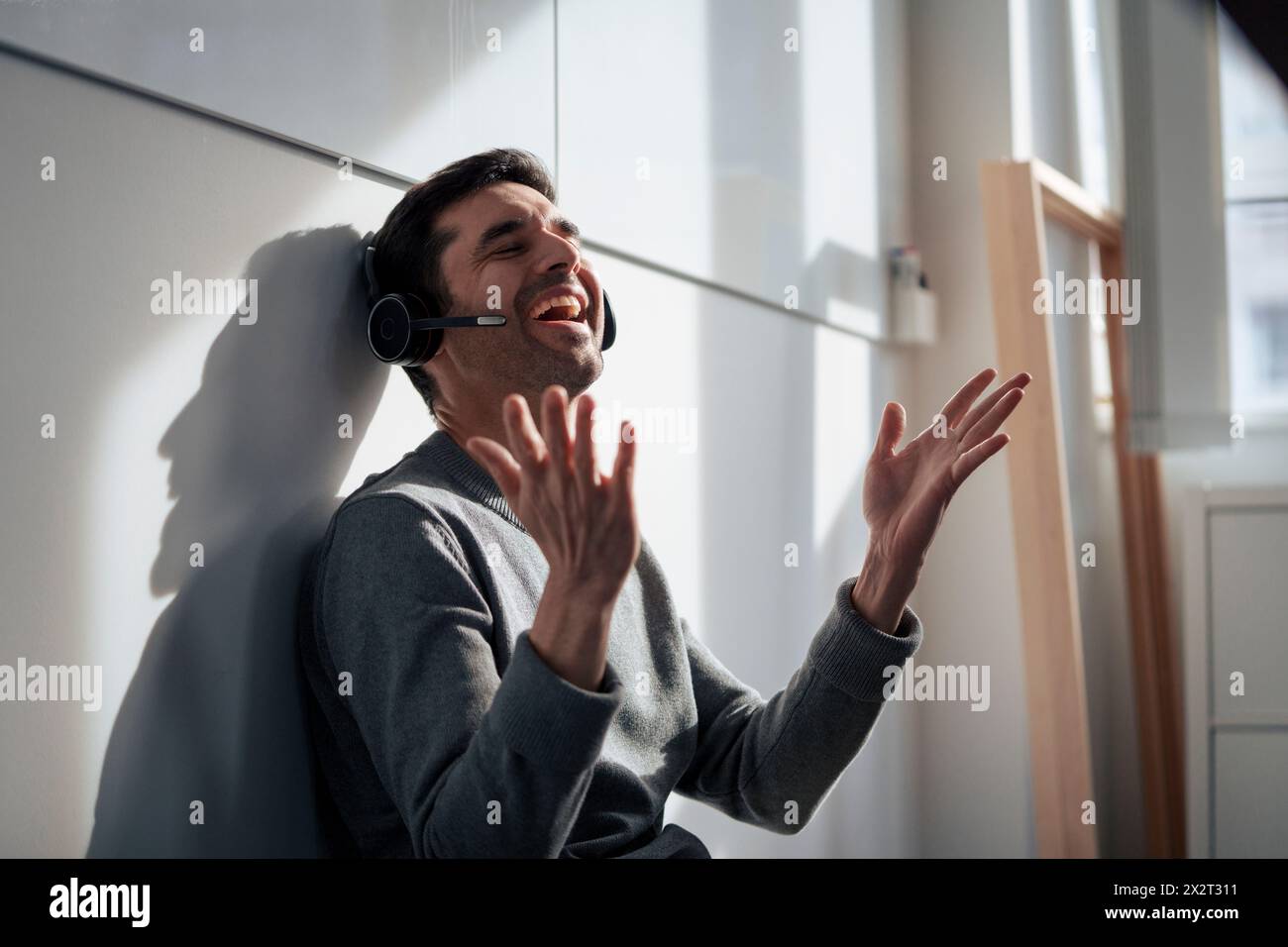 Fröhlicher, reifer Geschäftsmann, der über das Headset spricht Stockfoto