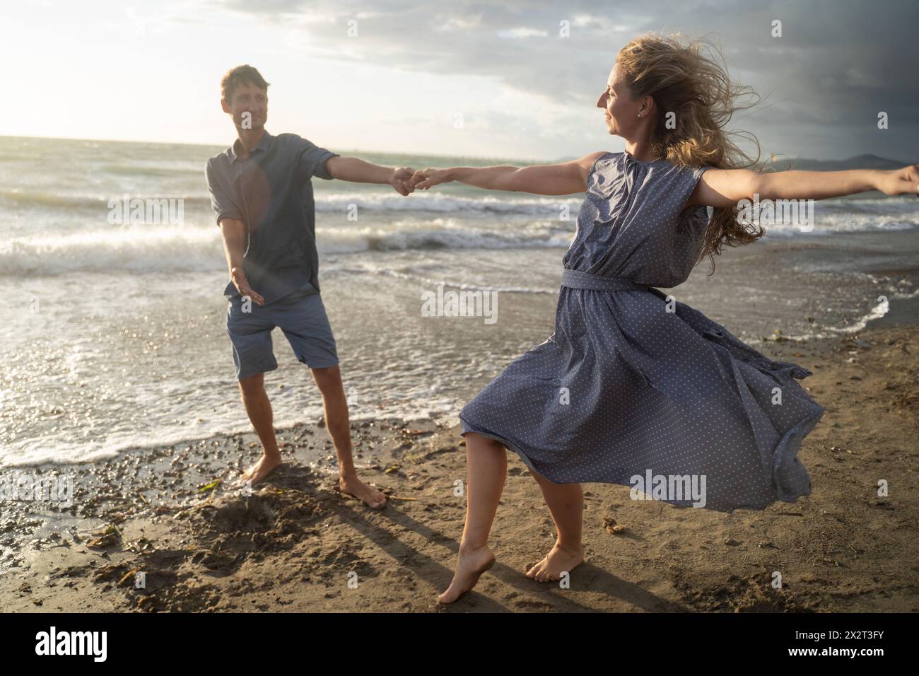 Ein Paar genießt Tanz am windigen Strand Stockfoto