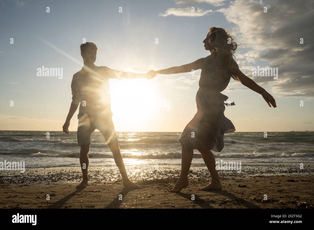 Hinterleuchtetes Paar, das am windigen Strand tanzen kann Stockfoto