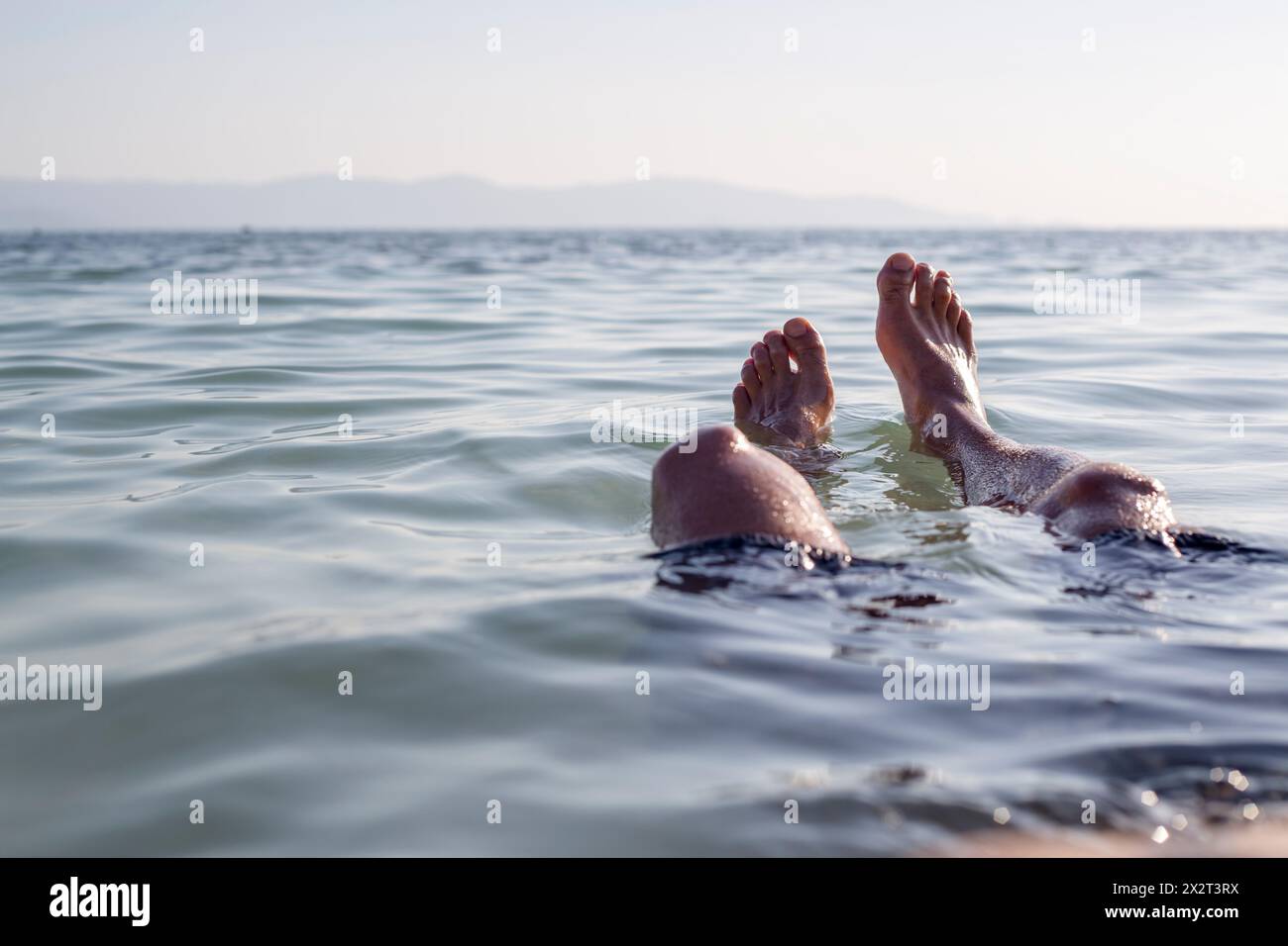 Die Beine eines Menschen tauchten im Urlaub ins Meer Stockfoto