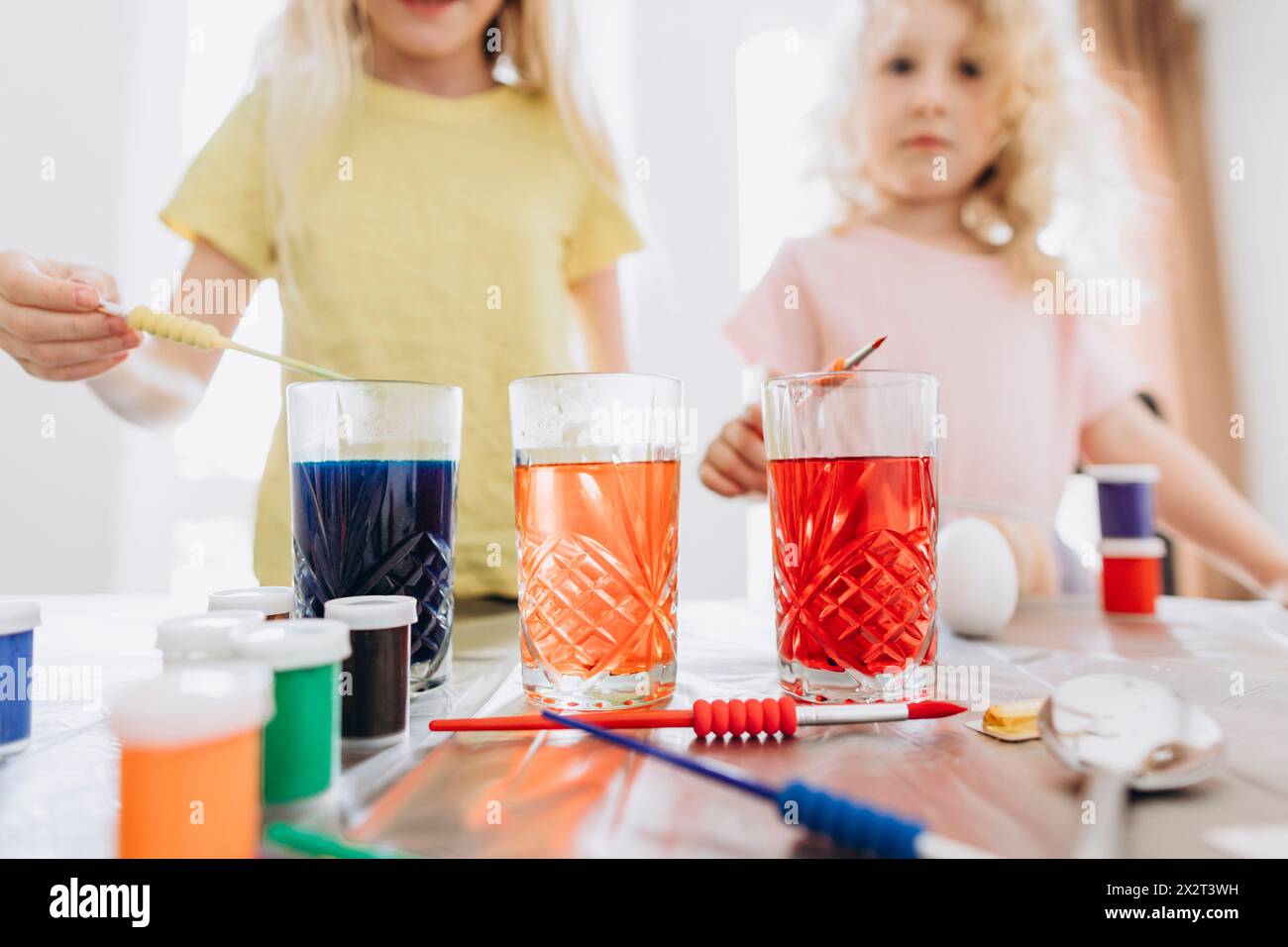 Schwestern bereiten Farbstoffe im Glas für Ostern zu Hause vor Stockfoto