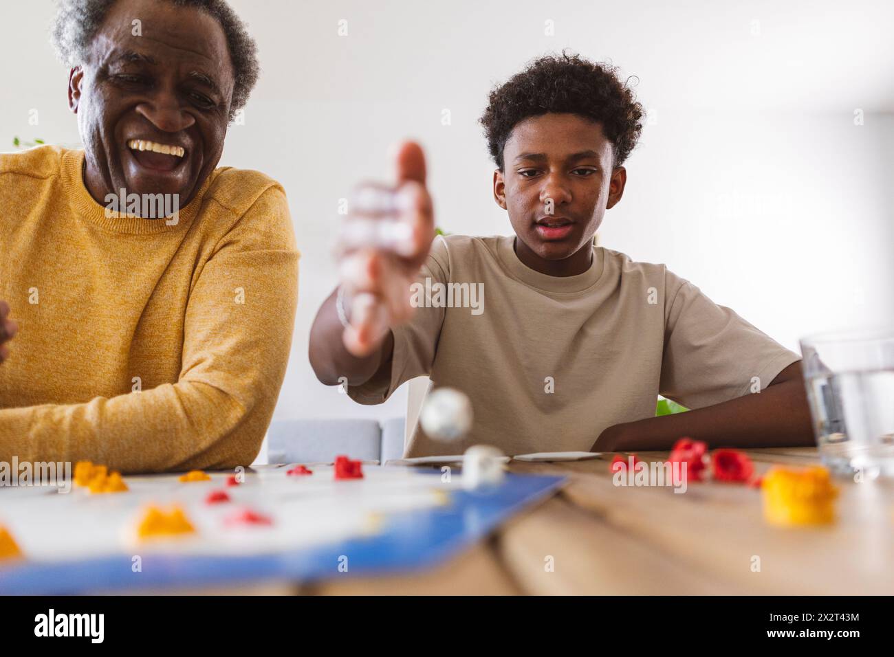 Glücklicher Seniorenmann, der mit Enkel zu Hause ein Brettspiel spielt Stockfoto