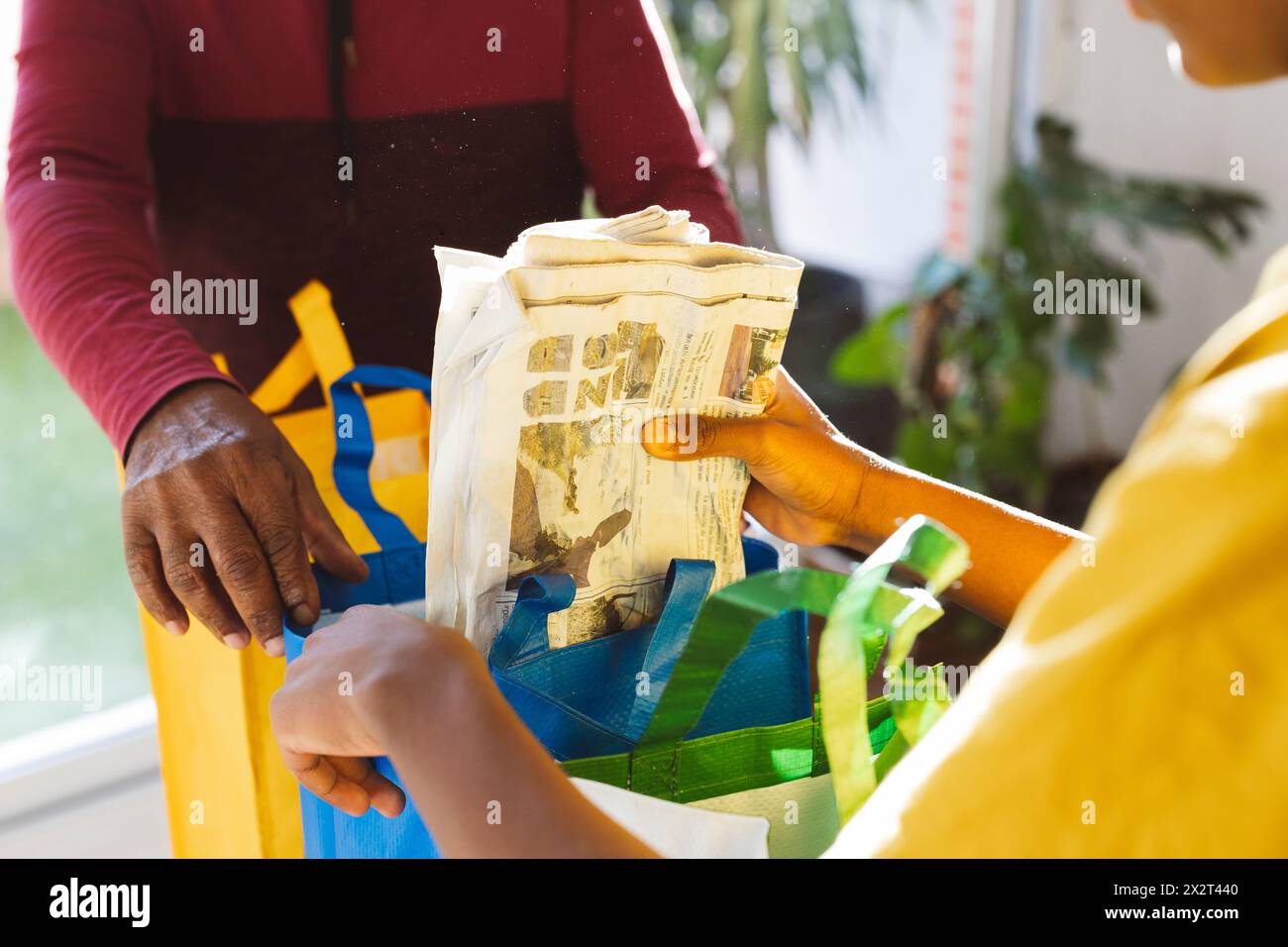 Enkel, der Papierkorb in einen Recyclingbeutel vor Großvater zu Hause steckt Stockfoto