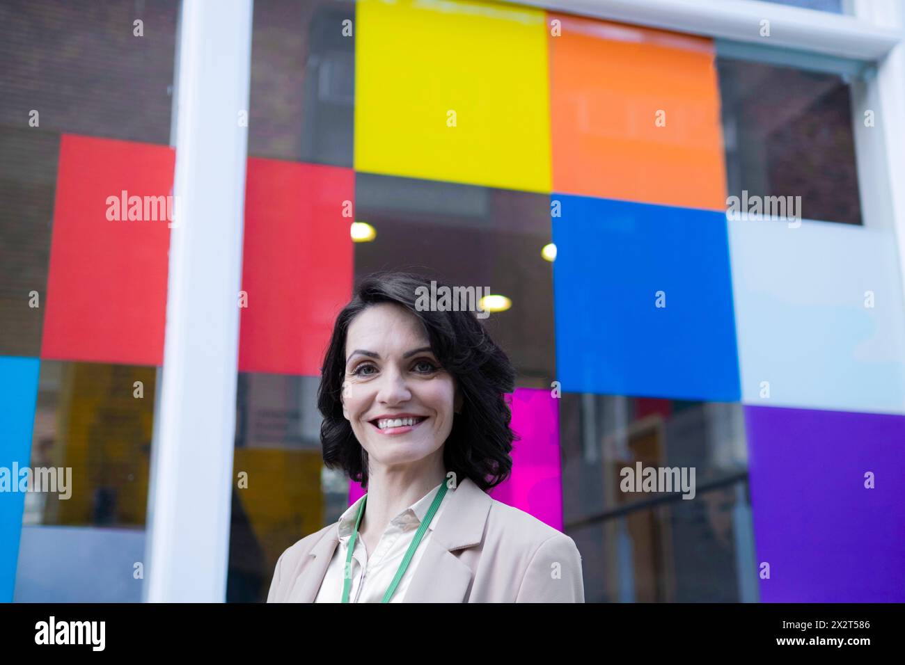 Lächelnde, schöne, reife Geschäftsfrau vor einem bunten Fenster Stockfoto