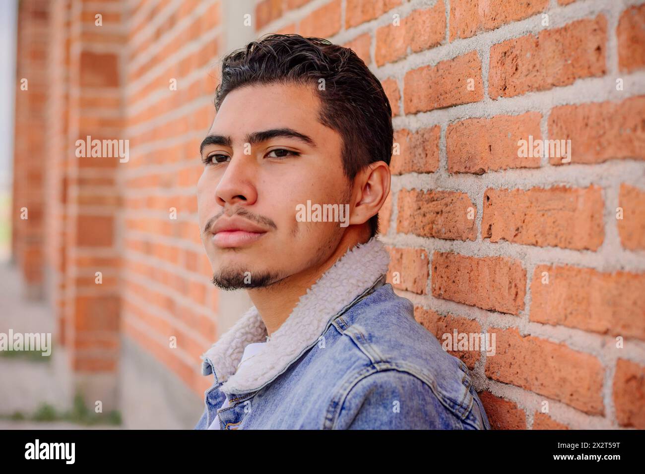 Nachdenklicher junger Mann an einer Ziegelmauer Stockfoto