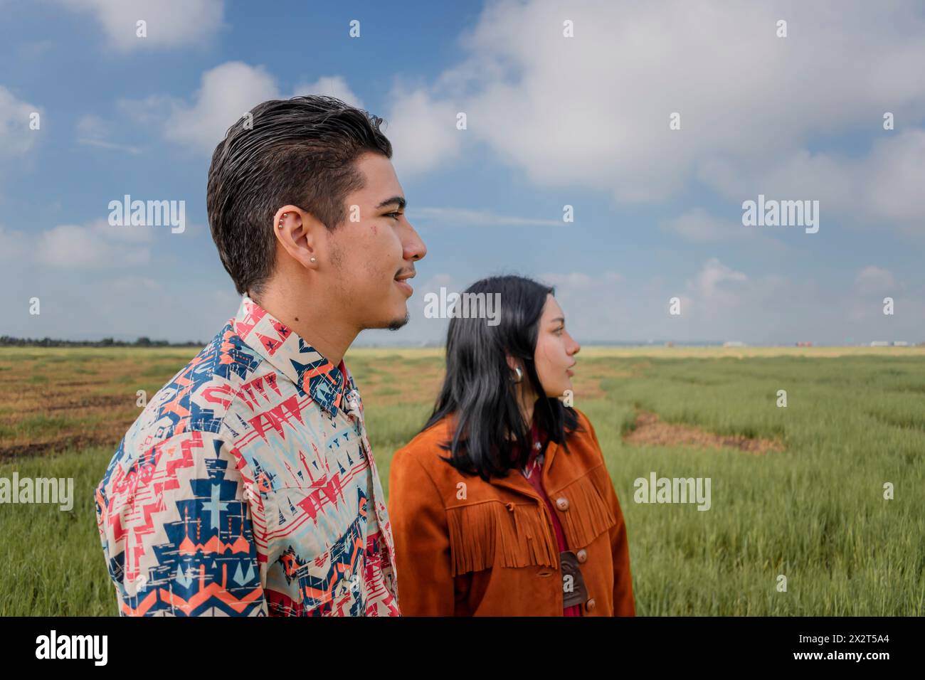 Ein junges Paar, das zusammen auf der Wiese steht Stockfoto Ein junges Paar, das zusammen auf der Wiese steht Stockfoto