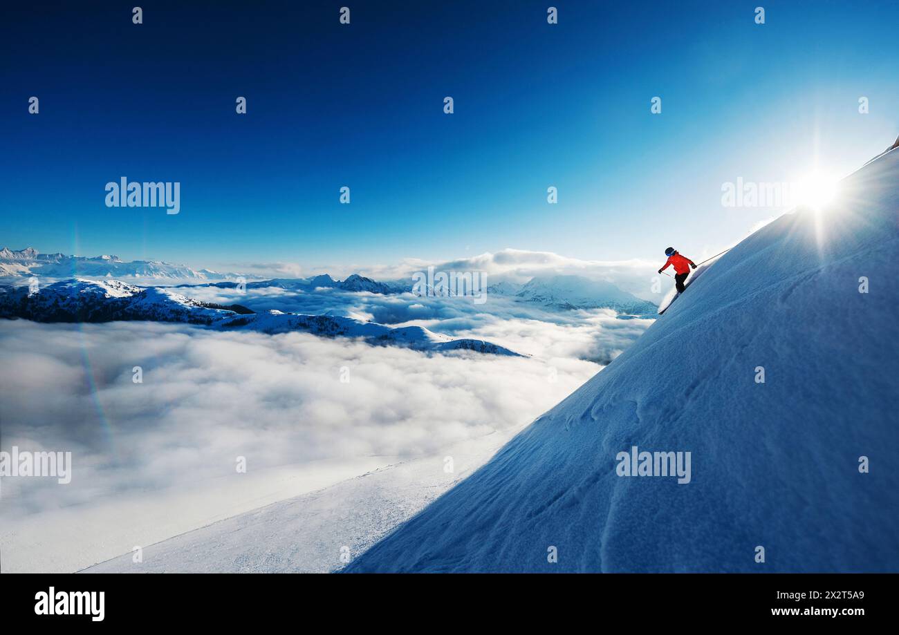 Österreich, Salzburger Land, weibliche Skiläuferin rutscht die Piste hoch über dem nebelumhüllten Tal hinunter Stockfoto