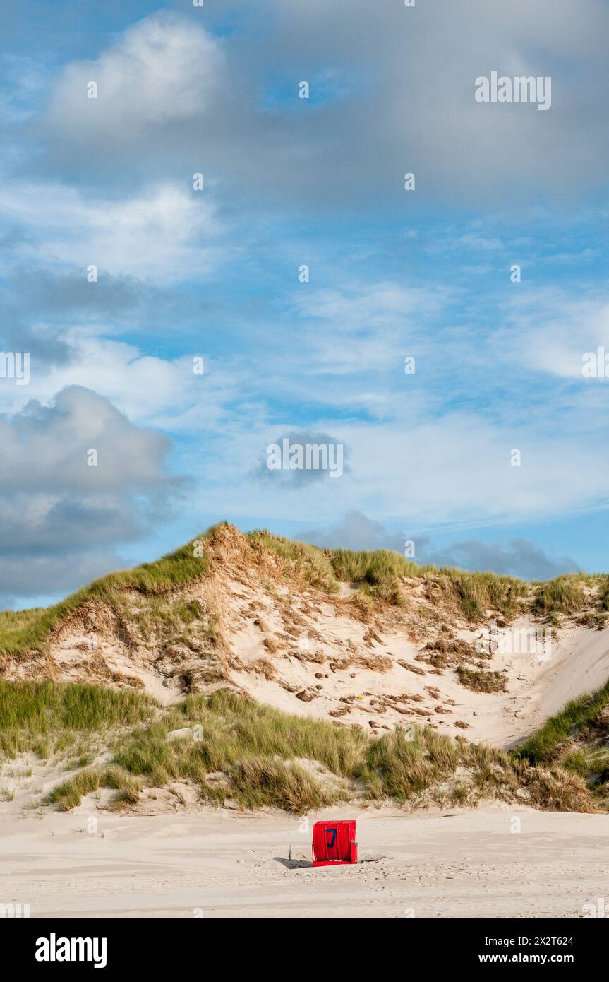 Deutschland, Schleswig-Holstein, Amrum, Wolken über einer Sonnenliege mit Kapuze am leeren Strand Stockfoto