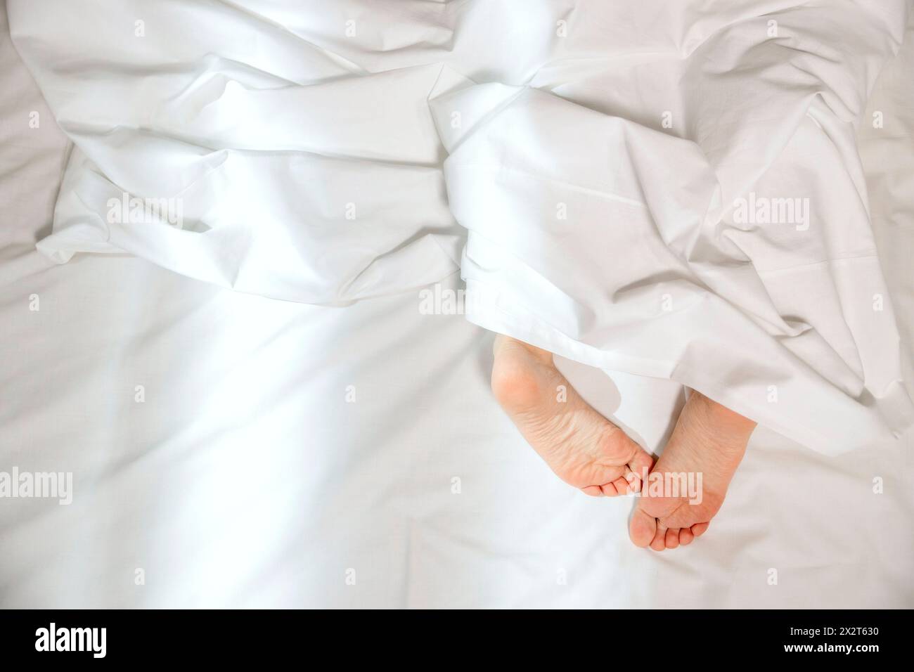 Füße aus der Decke auf dem Bett zu Hause Stockfoto