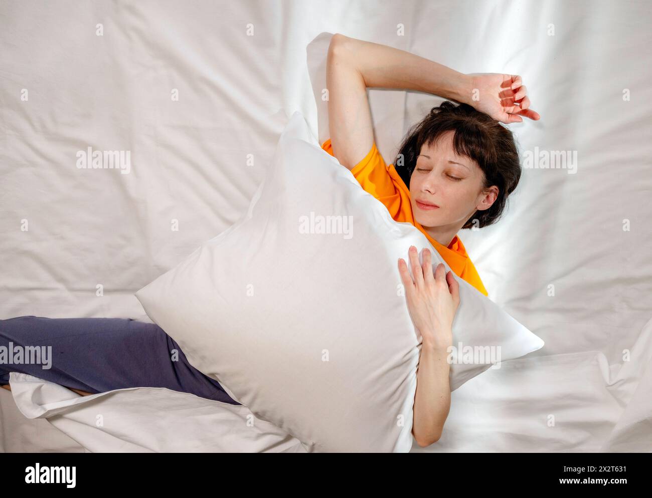 Frau mit Kissen, die zu Hause auf dem Bett schläft Stockfoto
