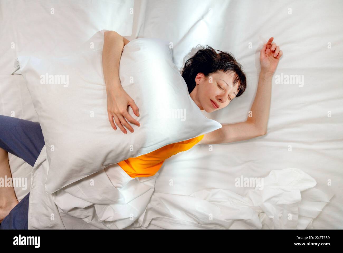 Frau schläft mit Kissen auf dem Bett zu Hause Stockfoto