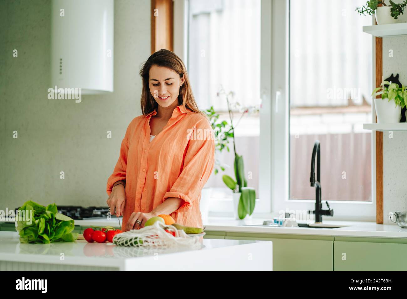 Frau, die zu Hause auf der Kücheninsel Obst hackt Stockfoto
