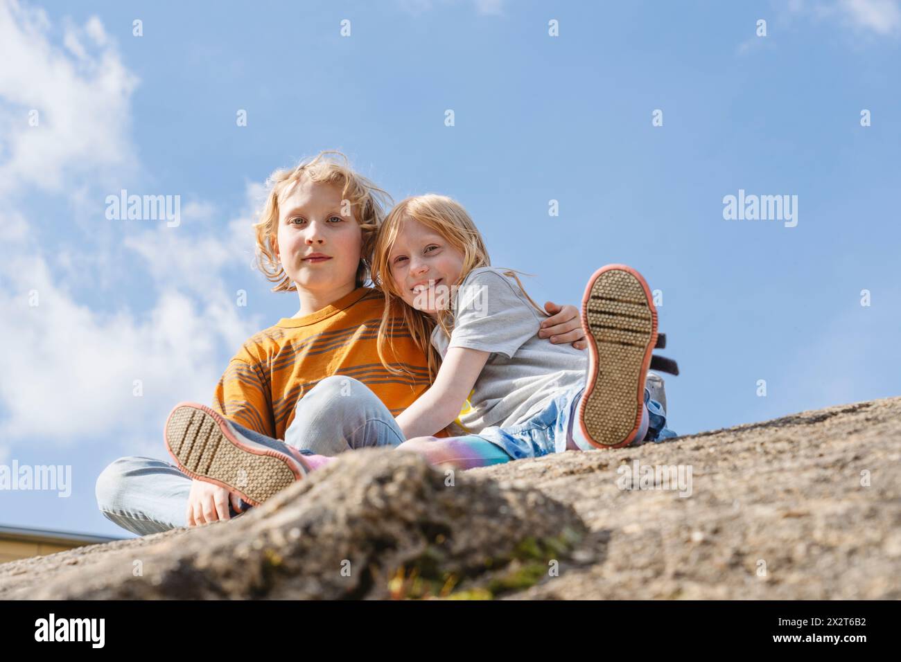 Junge sitzt mit Schwester auf Felsen Stockfoto