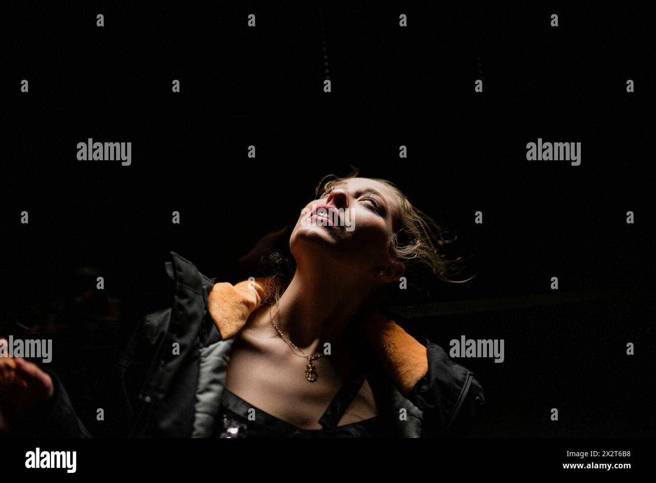 Beleuchtete junge Frau, die aufblickt Stockfoto