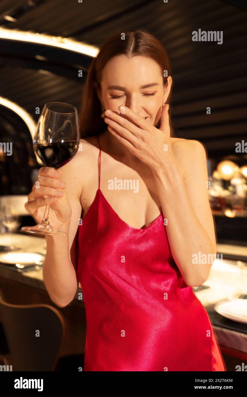 Eine junge Frau hält ein Glas Wein und lacht über den Club Stockfoto
