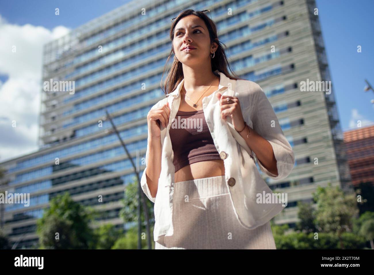 Besinnliche Geschäftsfrau vor dem Bürogebäude am sonnigen Tag Stockfoto