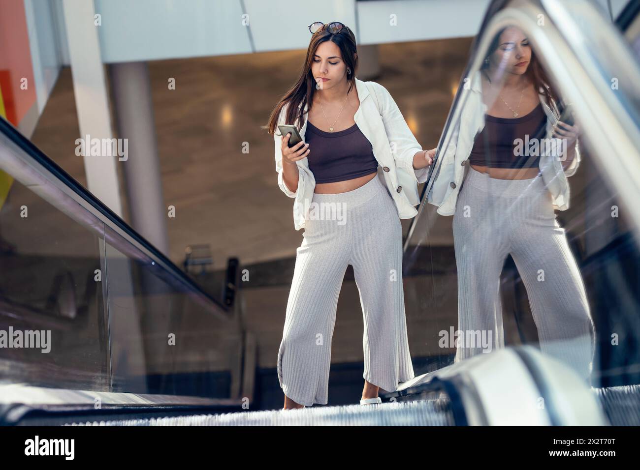 Geschäftsfrau mit Smartphone auf Rolltreppe Stockfoto