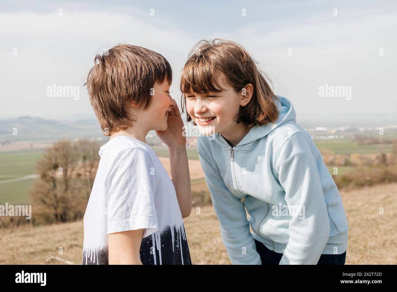 Bruder teilt sich das Geheimnis mit Schwester am sonnigen Tag Stockfoto