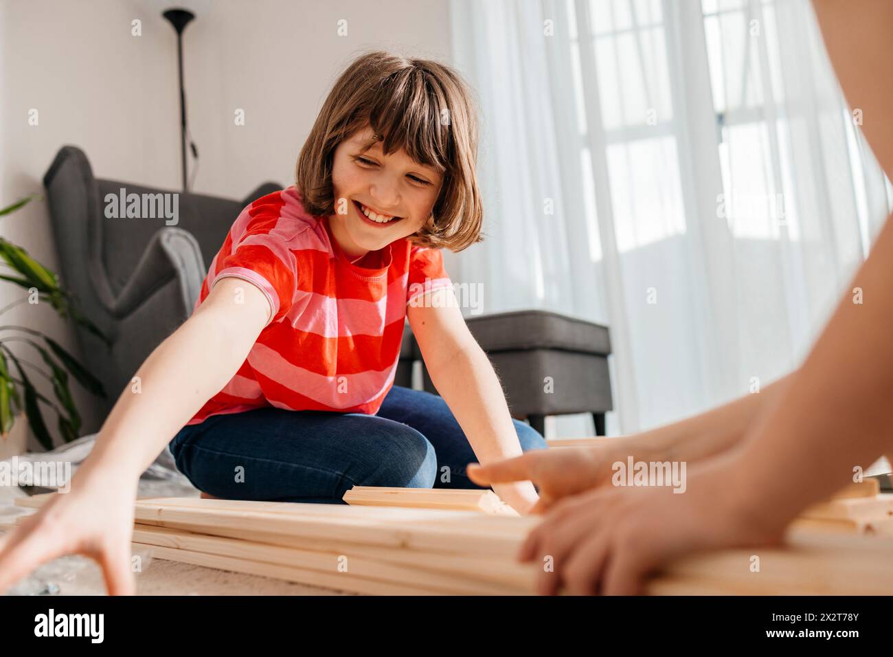 Lächelndes Mädchen und Bruder mit Dielen im Wohnzimmer Stockfoto