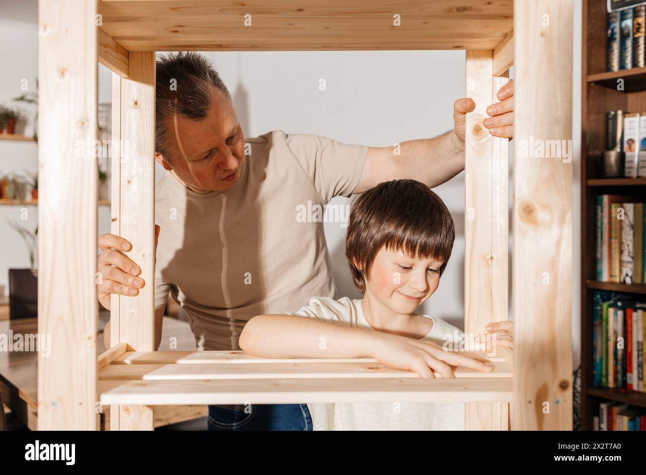 Vater und Sohn bauen zu Hause ein Holzgestell zusammen Stockfoto