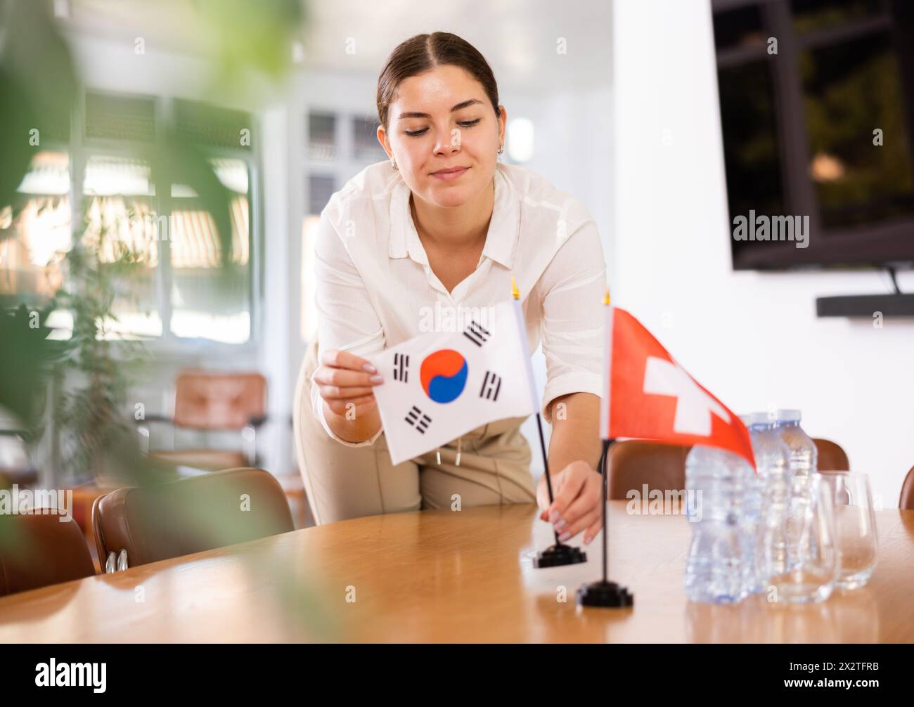 Weibliche Assistentin bereitet Konferenzraum für Diplomaten aus der Schweiz und Südkorea vor Stockfoto