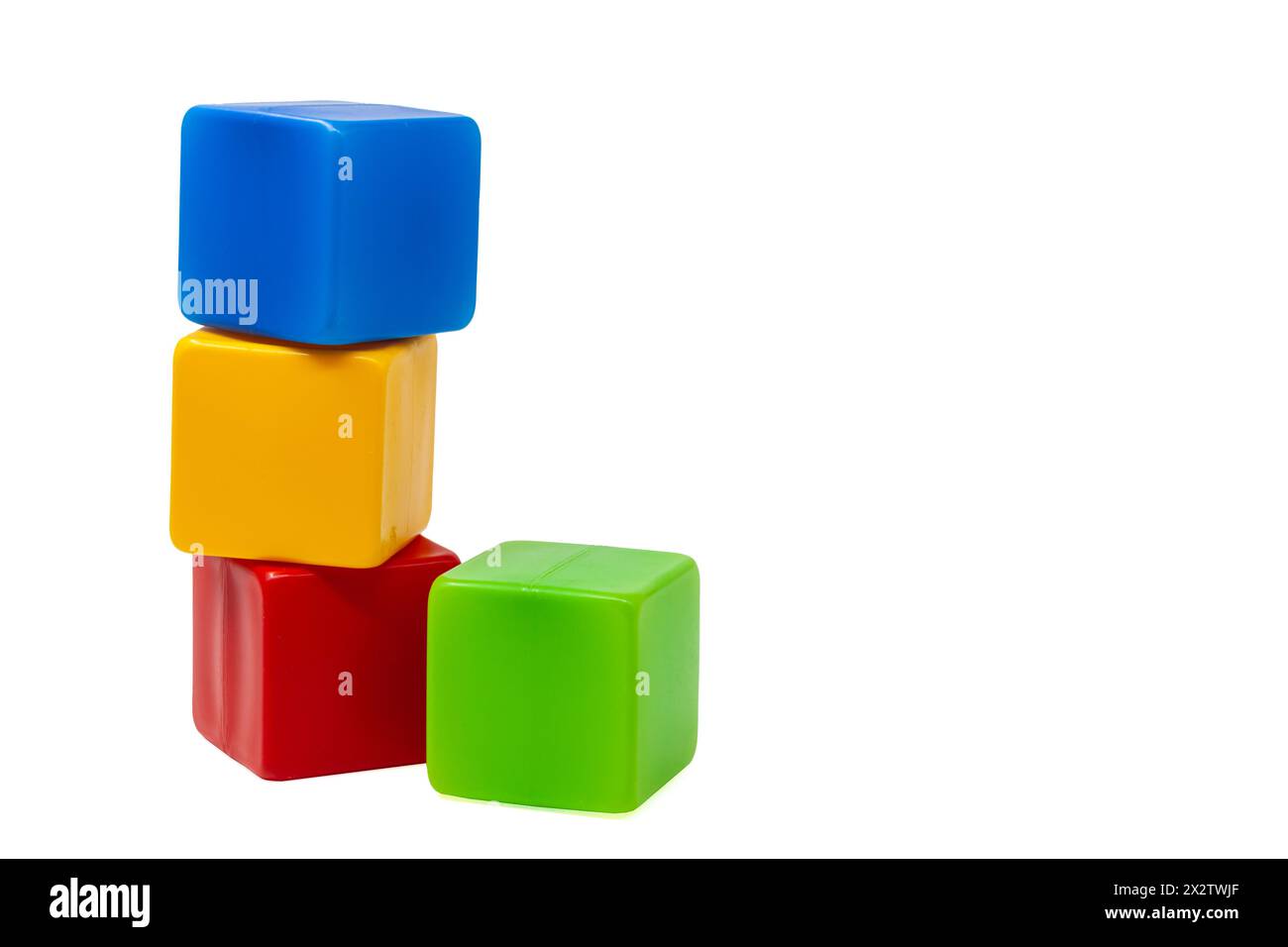 Mehrfarbige Plastikwürfel für Kinderspiele. Der gelbe Würfel steht oben auf dem roten und blauen Würfel, der grüne Würfel daneben. Eins auf eins. Stockfoto