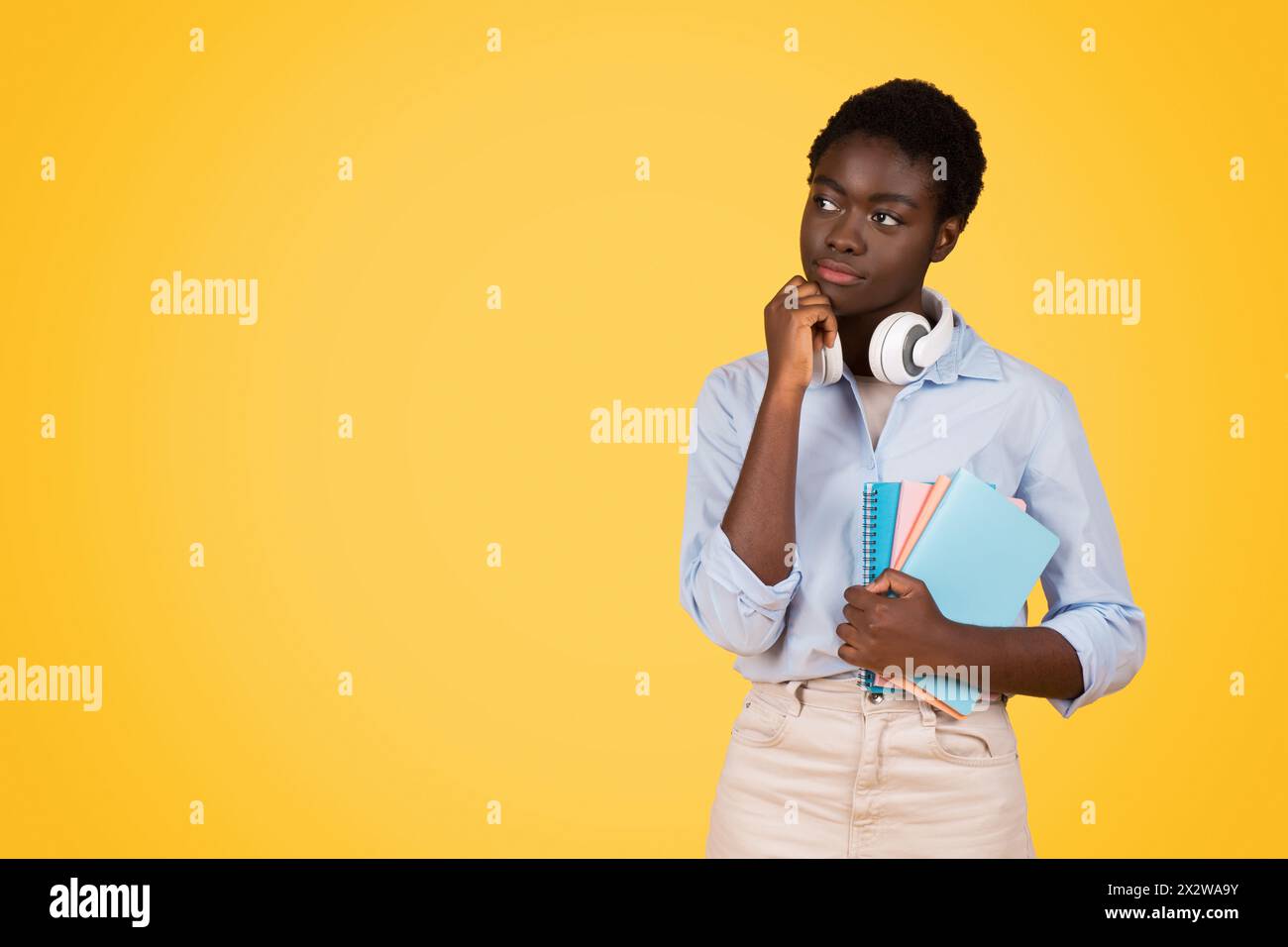 Nachdenkliche afroamerikanerin mit Notizbüchern auf Gelb Stockfoto