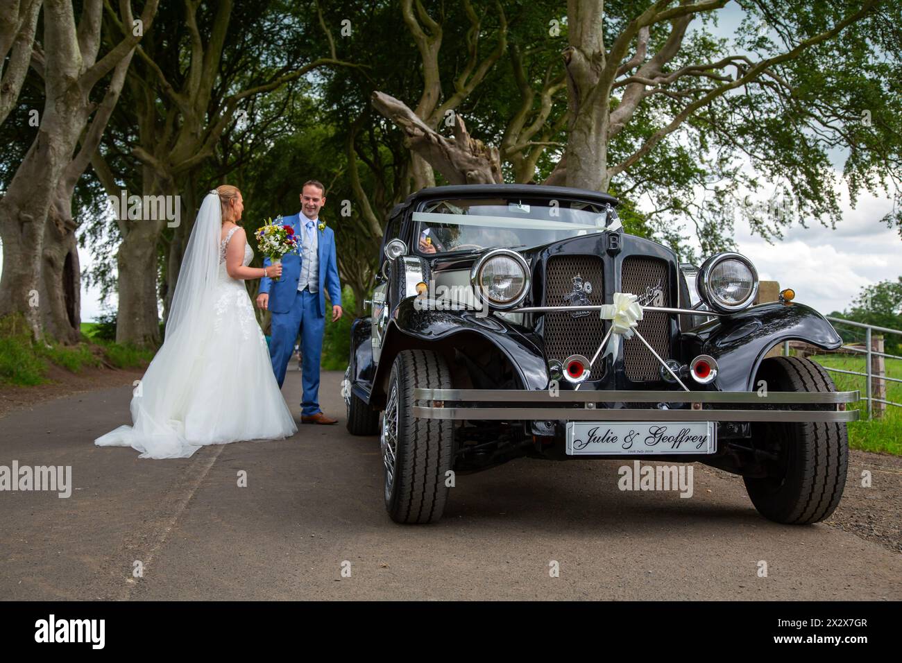16.07.2019, Stranocum, Nordirland, Vereinigtes Königreich - Hochzeitspaare, die in einem Vintage Bentley reisen, besuchen Sie die Dark Hedges, eine majestätische Buchenallee Stockfoto