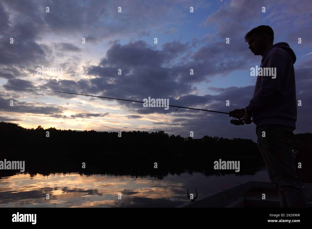 14.10.2022, Dranse, Brandenburg, Deutschland - Silhouette: Junger Mann fischt an einem See in der Abenddämmerung. 00S221014D205CAROEX.JPG [MODELLVERSION: JA, EIGENSCHAFTSVERSION Stockfoto