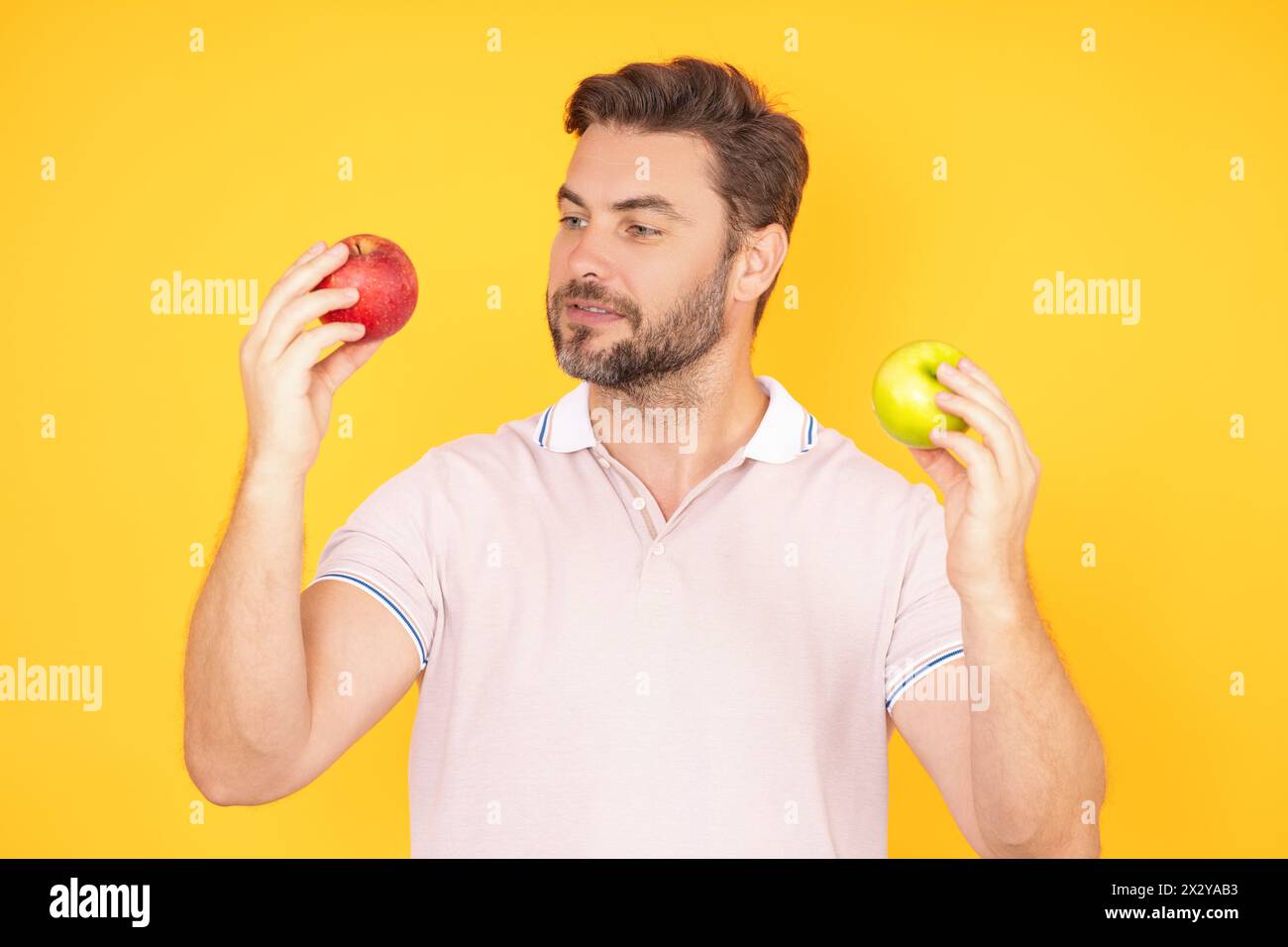 Stomatologisches Konzept. Ein Mann mit perfektem Lächeln, der Apfel auf einem gelben, isolierten Studio-Hintergrund hält. Mann isst grünen Apfel. Porträt des Mannes mittleren Alters mit Stockfoto