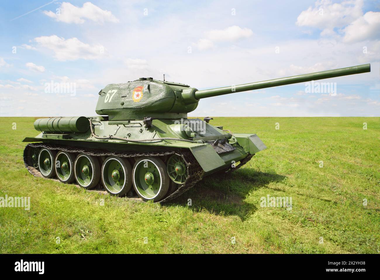 Der alte legendäre Tank T-34/85 auf dem grünen Feld am sonnigen Sommertag. Stockfoto