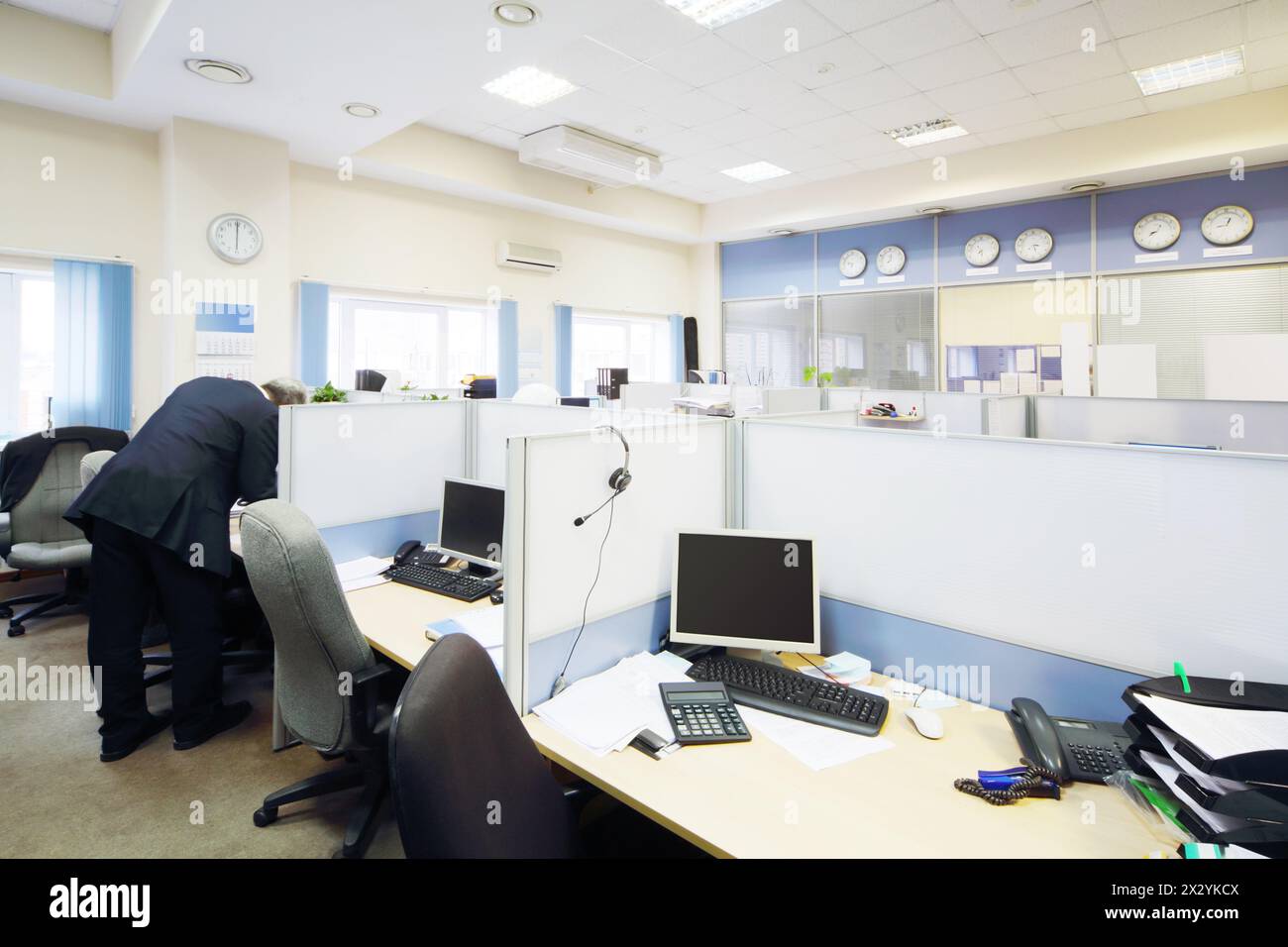 Die Menschen arbeiten in großen, hellen Büros mit getrennten Arbeitsbereichen und Desktops. Stockfoto