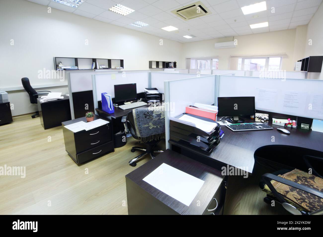 Leere Arbeitsbereiche mit Desktops und Dokumenten, die durch Partitionen getrennt sind. Stockfoto