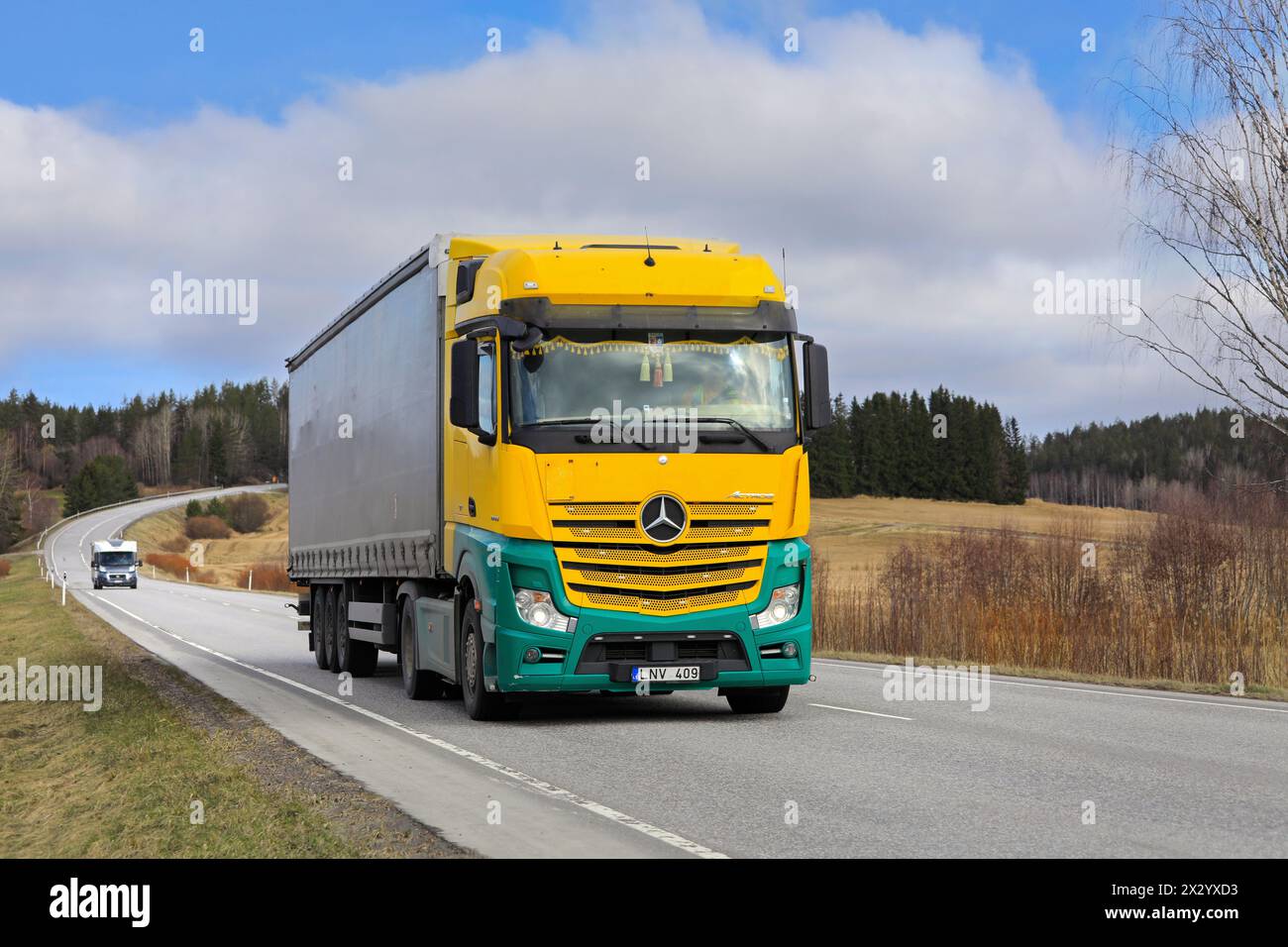 Der gelb-grüne Mercedes-Benz Actros 1845 zieht an einem Frühlingstag einen Auflieger entlang der Autobahn. Salo, Finnland. April 2024. Stockfoto