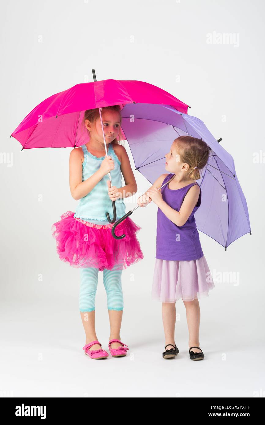 Zwei Mädchen in bunten Gewändern mit bunten Regenschirmen Stockfoto